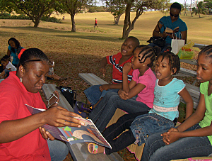 Annice Canton reads to kids under the trees at UVI.