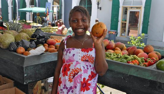 Skylarr Lee shows off a mango from St. Croix farmer Pennyfeather's produce.