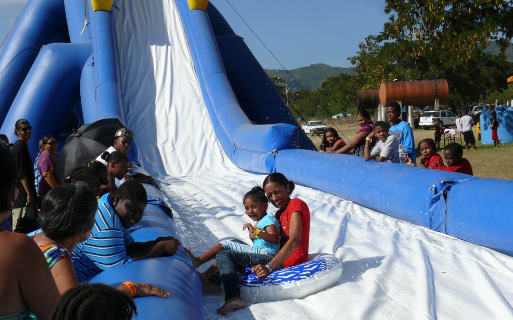 Shantee Sookraj takes her daughter, Anjali, for a cooling trip down the waterslide at Agrifest 2010 Monday.