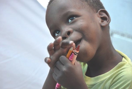 A Haitian orphan is delighed with his new crayons. Photo by Carmen Partridge.