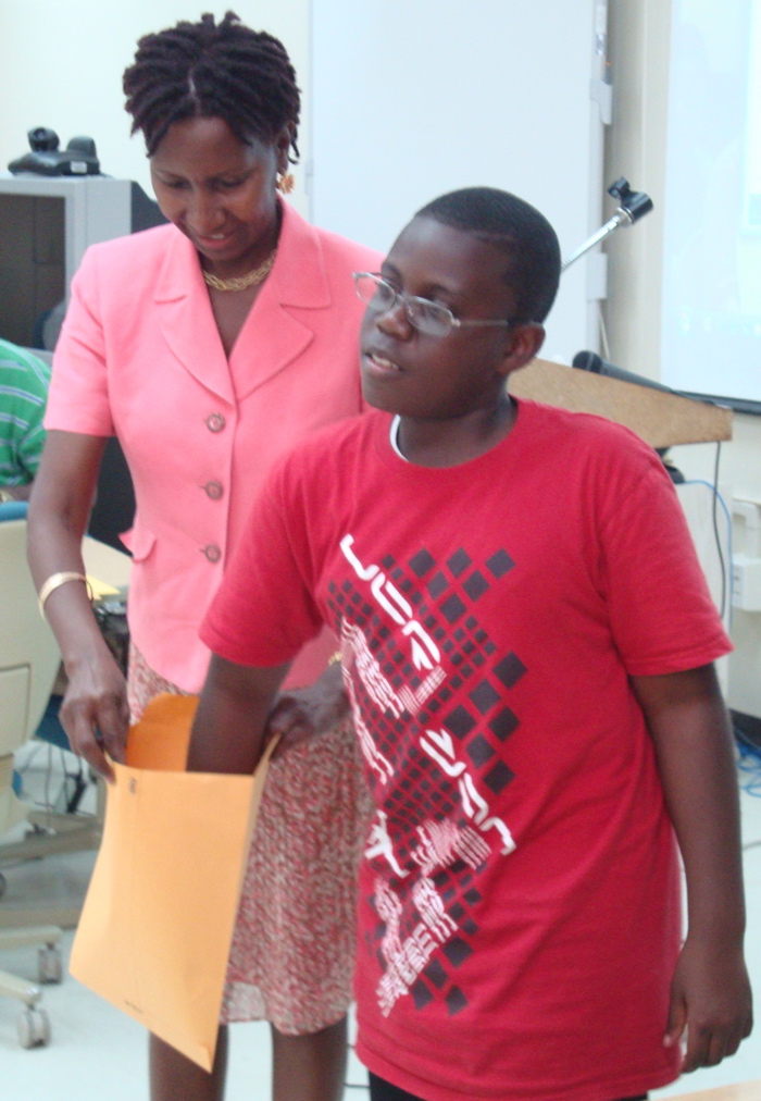 Good Hope School sixth-grader Gershom Thompson draws his number for the St. Croix District Spelling Bee. Holding the envelope is contest coordinator Charlene Matthew.