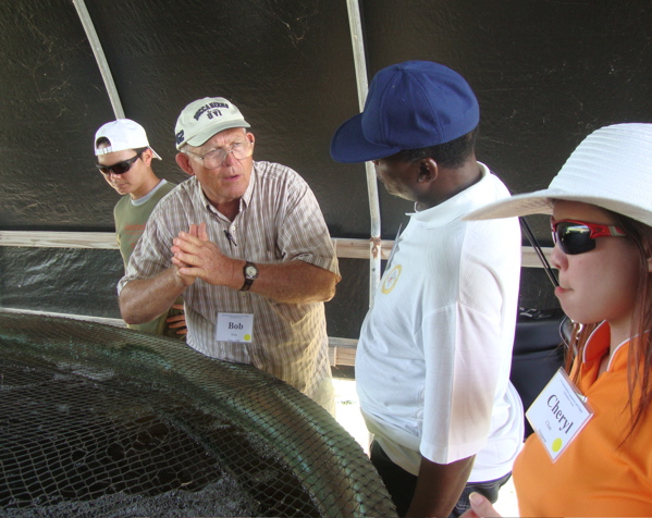 International participants talk around a tank of tilapia during the 12th Annual International Aquaponics and Tilapia Aquaculture Course.