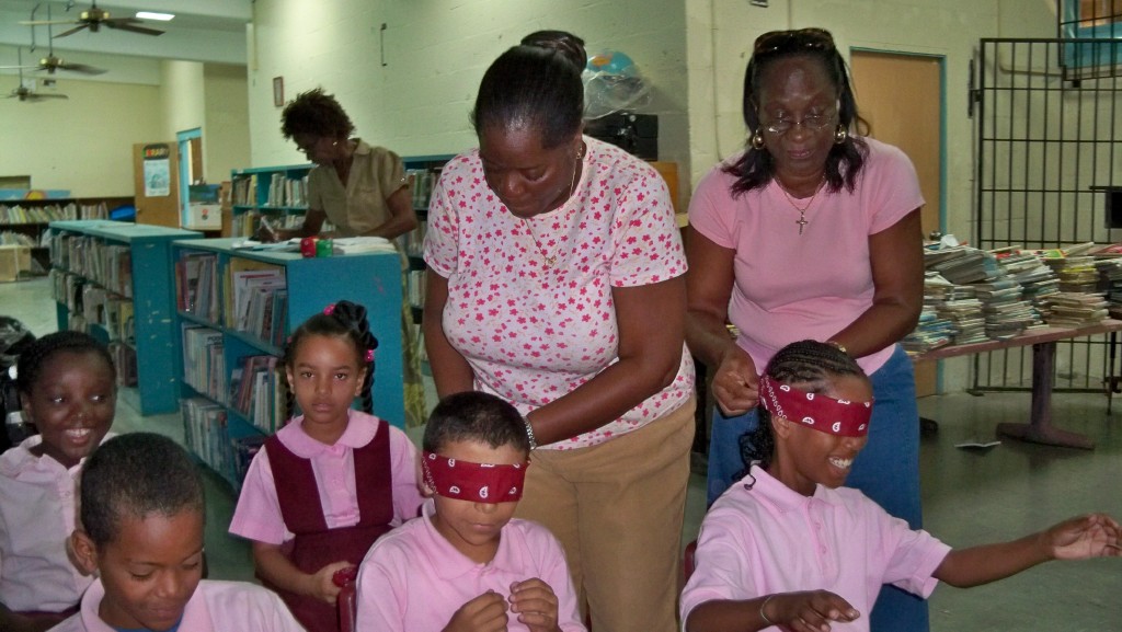 Third-grade teacher Carol Frank (left) and Sheryl Muckle-Williams tie bandannas on students.