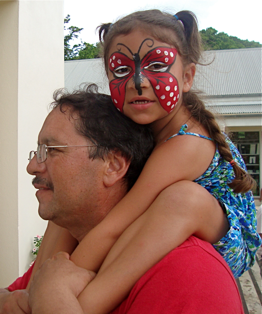 With her face brightly painted, Abigail Moreno, of Houston, rides the shoulders of her father, Alejandro.