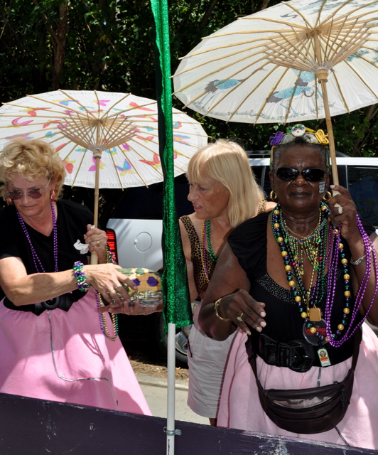 Members of Krewe De Croix pass out painted coconuts to the crowd lining the parade route.