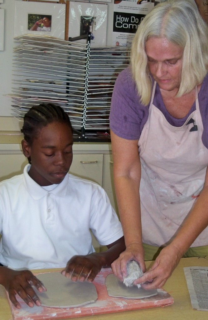 Student Reuben James and ceramic artist Sara Lee Hayes work on a clay head.