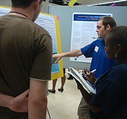 Jeffrey Renchen (rear) discusses his project on genetics with two area high school students.