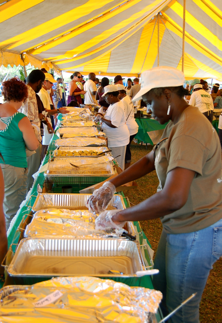 A line of volunteers on the right serves entrees to a longer line of diners on the left.