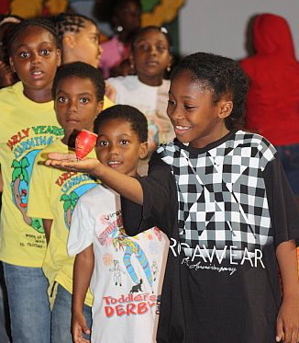Youngsters watch wide-eyed as 8-year-old Jahquan Nesbitt holds a spinning top in the palm of his hand.