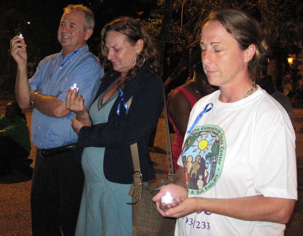 Andrew Rutnik and Bonny Corbeil of Crime Stoppers and Terri Lamb of the St. John Community Crisis Center hold candles to remember victims of crime.