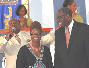 Paster Gerald McDonald, back left, with mike, gives and anniversary blessing to Marilyn Braithwaite-Hall and her husband, UVI president David Hall.