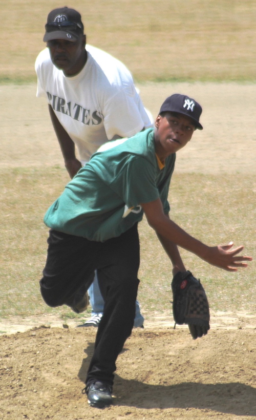Suns’ Daren Steven delivers a pitch while the game’s lone umpire watches intently.