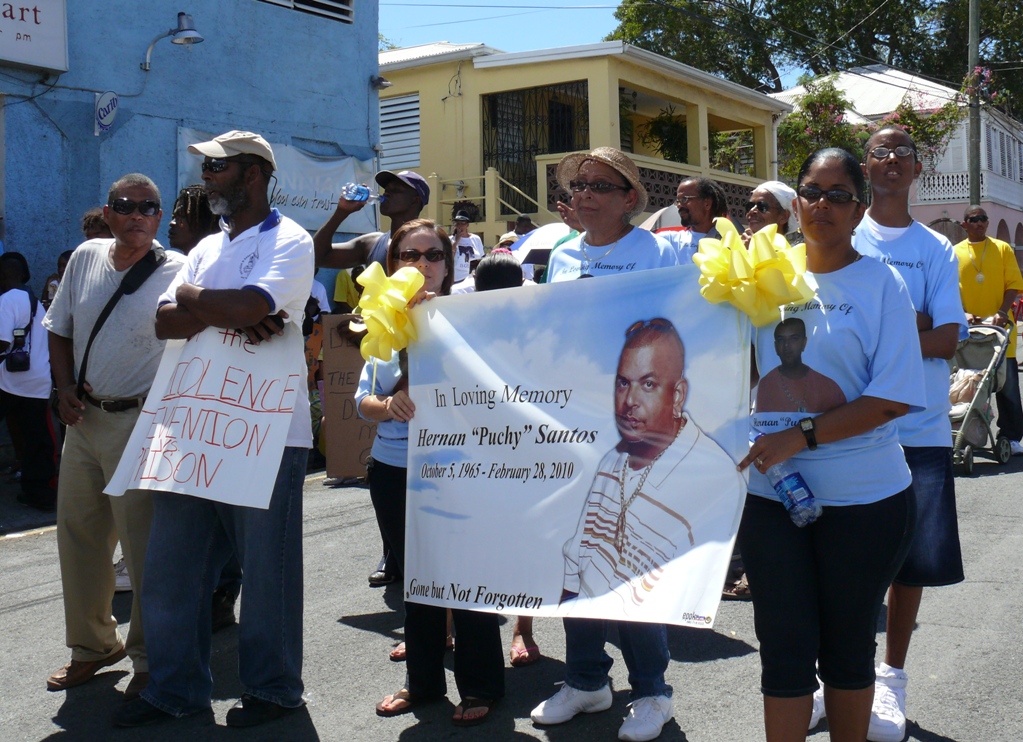 The Santos family carries a banner commemorating Hernan "Puchy" Santos, who was murdered earlier this year in Frederiksted.