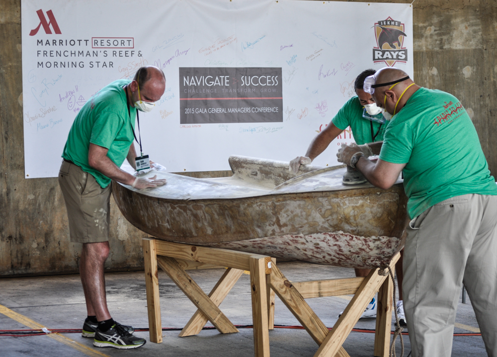 Marriott employees sand one of IEKHS's dinghies in the Frenchman's Reef parking lot.