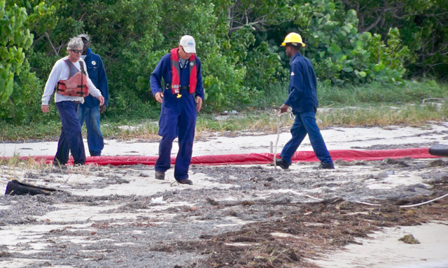 A WAPA crew assesses the fuel spill on the sand near the Estate Richmond dock. (Carol Buchanan photo)