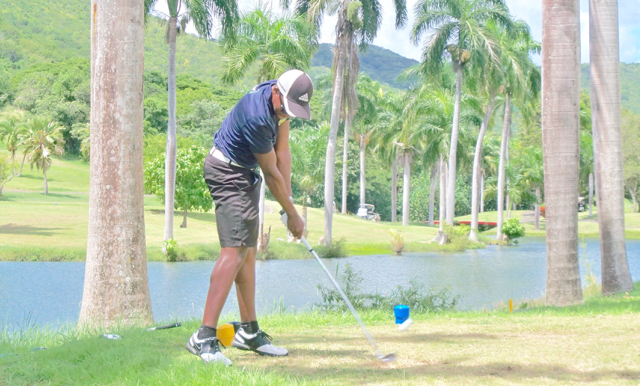 A golfer drives one over the water.