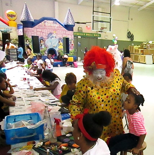 Ann Jerris as JayJay the Clown paints the face of 6 year-old A'Jiydah Schuster while other kids do craft projects and others play in the bouncy structures.