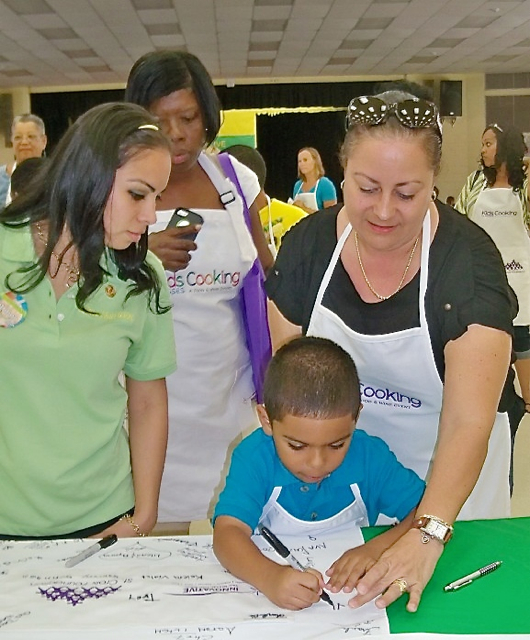 Bianca Francis, left, Ayngel Ayala, age 4, and Dalia Austin sign an apron for Michelle Obama