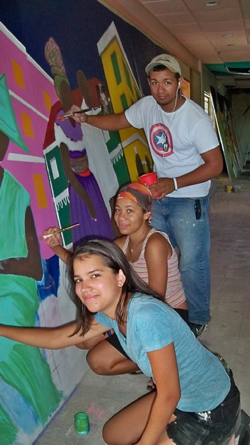 From bottom up, Katherine Bishop, Cherise Finney and Victor Cepeda paint the parade mural.