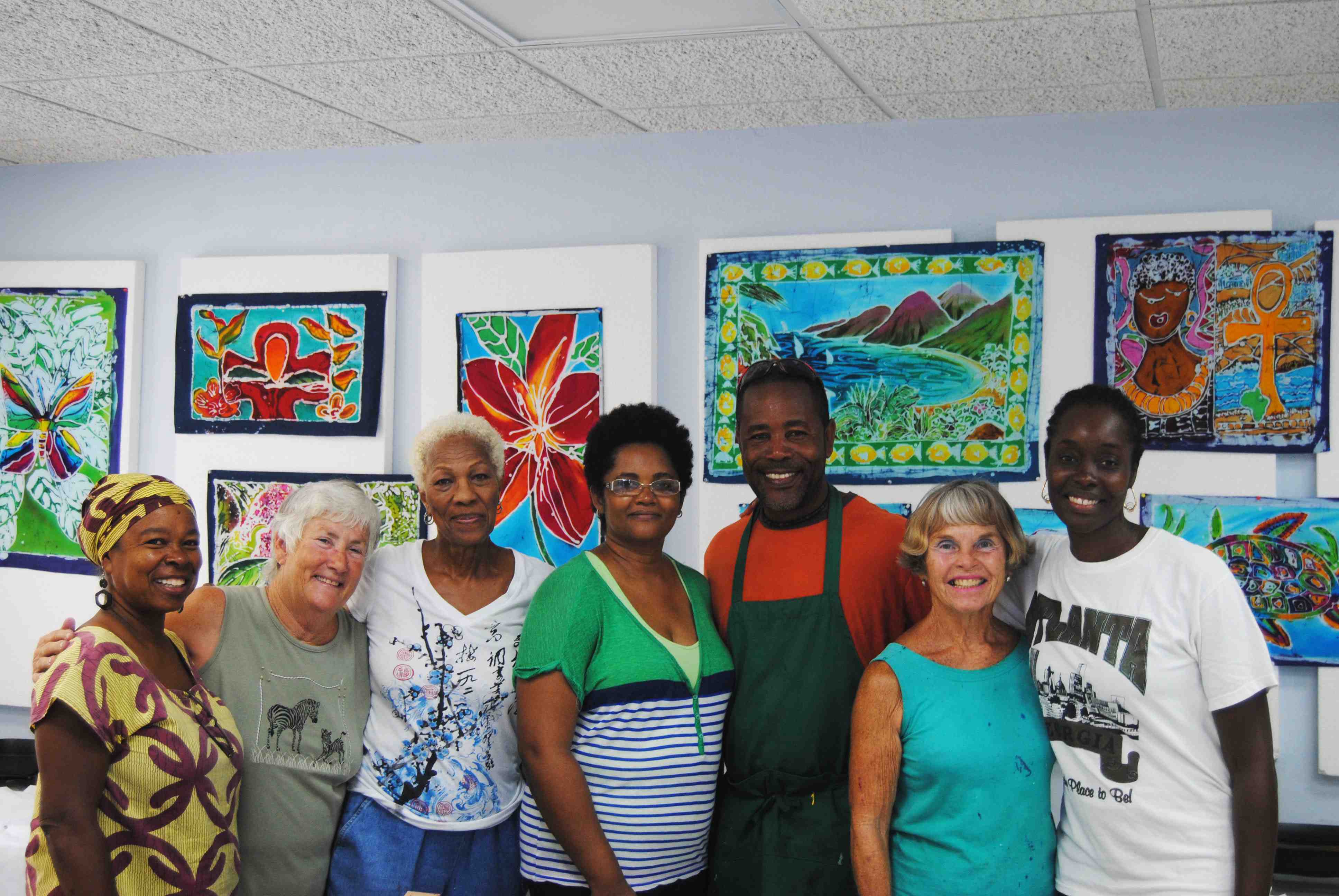 Anna Francis, left, Kathy Butler, Mary Davis, Sharon Nieves, Henderson Reece, Caryl Johnson and Karen John-Mukhi stand in front of some of the students' work from the batik workshop.