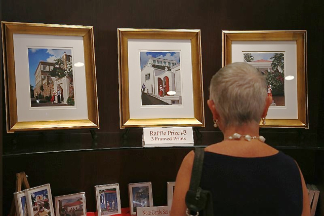 A patron browses the 'Lady in Red Visits' exhibit at Yacht Haven Grande.