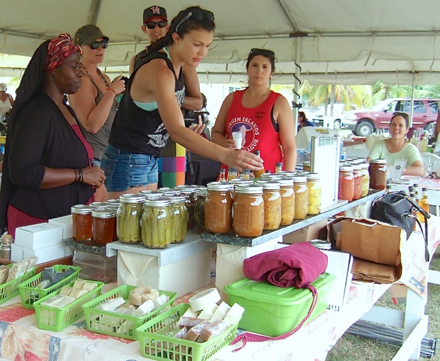 Customers look over Ras Sonrise and Daughter Farm's wares at the VIDOA's value-added market Saturday. 