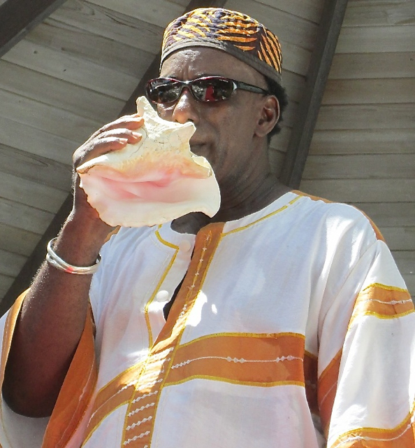 Mano Boyd blows the conch to open the St. John Festival Food Fair Sunday.