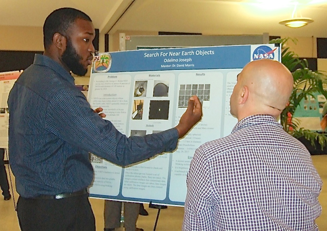 Odelmo Joseph explains his UVI research project Saturday to symposium judge and math instructor Celik Ekici.