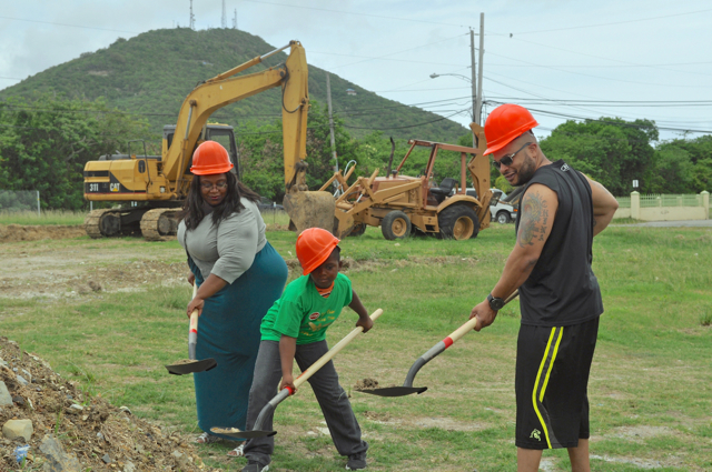 From left, Tamisha Thomas, Tejaun Porter and Maurice Roebuck wear hard hats to scoop dirt from what will be a new building and addition to the Mon Bijou Community Center.