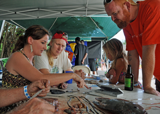 From left, volunteers Kynoch Reale-Munroe and Emily Weston show Reef Jam visitors the innards of a dissected tilapia, lionfish and squid.