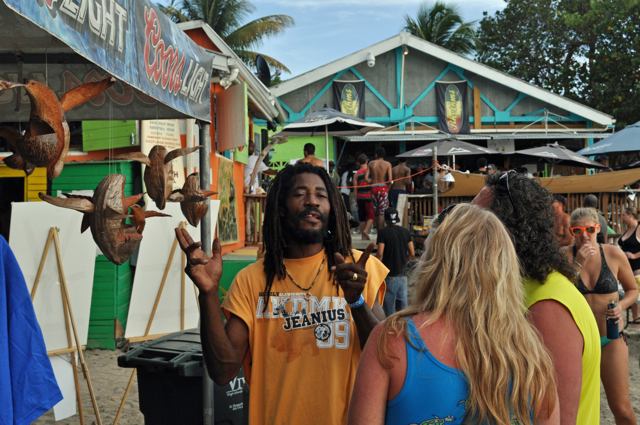 Reef Jam art vendor Buds Leo explains his pieces to two attendees. Leo takes dried coconuts and carves them into sea turtles that he hope tourists will bring home as a keepsake from St. Croix.