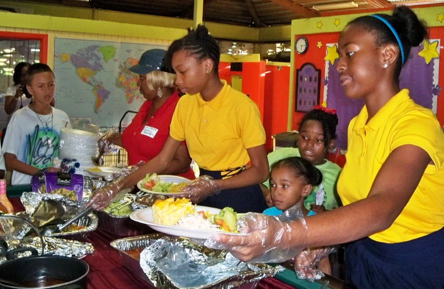 Twelve-year-old Laurie Cedeno, right, serves dinner to B&GC members.