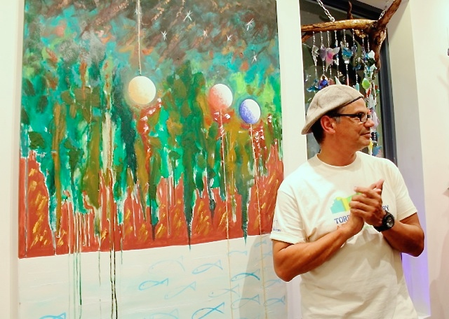 Artist Ensor Colon displays his work, 'Where Are We Going to Live?' at the Defending Paradise art exhibition.