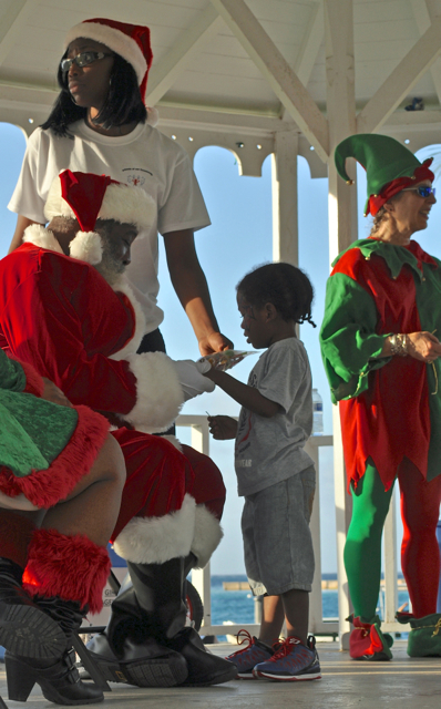 Santa gives treats to one of the many children who came out to see him Saturday to the bandstand at Fort Christiansvaern.