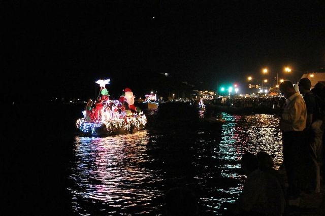 Lighted boat parade entries sailing along the St. Thomas waterfront.