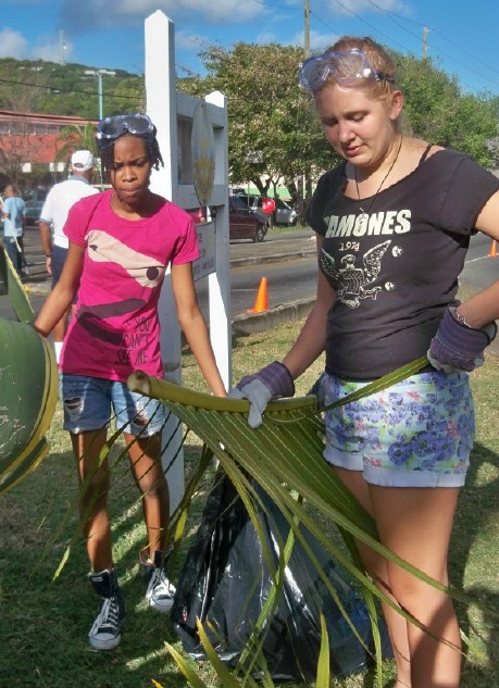 Interact members Brandy Tutein, left, and Adara McCormick prune palms Saturday at the Golden Rock traffic triangle..