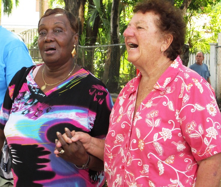  St. John resident Eleanor Parilla and former resident Charlotte Fish join hands to sing "We Shall Overcome."