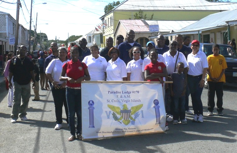 Maria Espinosa and Brieanna Ross hold the banner for Paradise Lodge 170 of the Masons, with masons from the Gems Youth, the Cornerstone Lodge and Paradise Lodge marching behind.