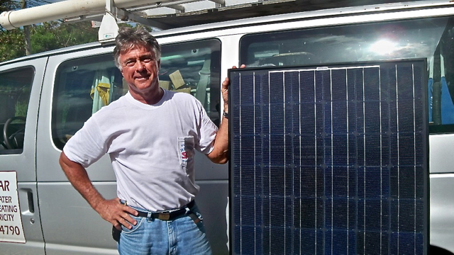 Beecher Higby III displays a photovoltaic solar panel.