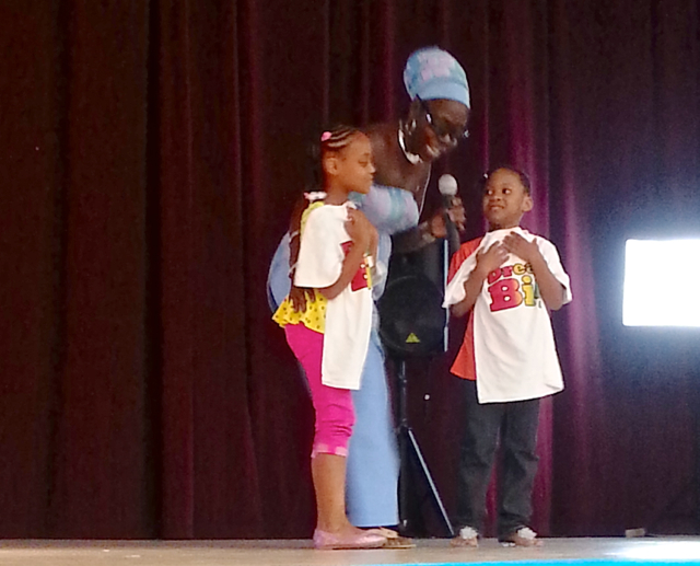 Mada Nile presents T-shirts to two young audience members.