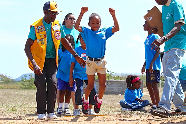 Volunteers cheer on an athlete in the standing long jump.