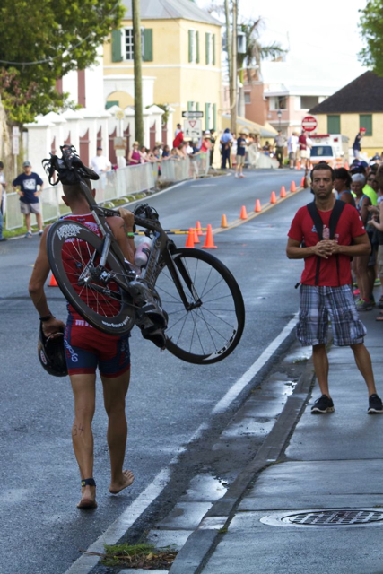 A competitor carries his bike back to the transition area after a flat tire knocked him out of the race.