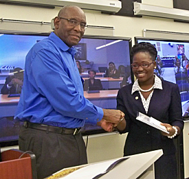 UVI President David Hall and UVI student Sheena Tonge, with the St. Thomas videoconference in the background.