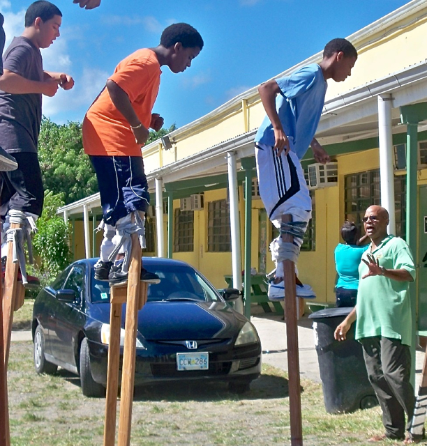 Willard John, right, instructs young students on the art of stilt dancing.