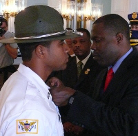 Superior Court Marshal Darwin Dowling (right) affixes the badge on new Marshal Wilbur Francis in August.