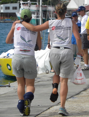 Julie Bossard, right with ankle brace, is assisted by a crewmate to her boat before the petit finals of the Carlos Aguilar Match Racing Regatta.