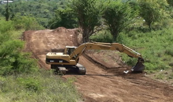 A backhoe carves out the auxiliary road to Tutu.