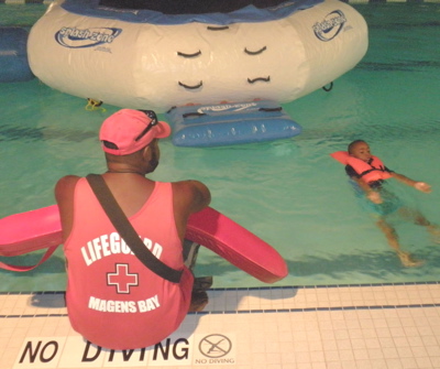 A St. Thomas Swim Association lifeguard watches a young swimmer on Friday Fun Night. 