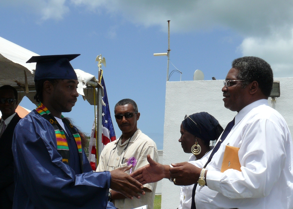 V.I. BOC Director Julius Wilson congratulates Golden Grove inmate Akeel Codrington on his high school diploma at a ceremony just outside the prison walls Friday.