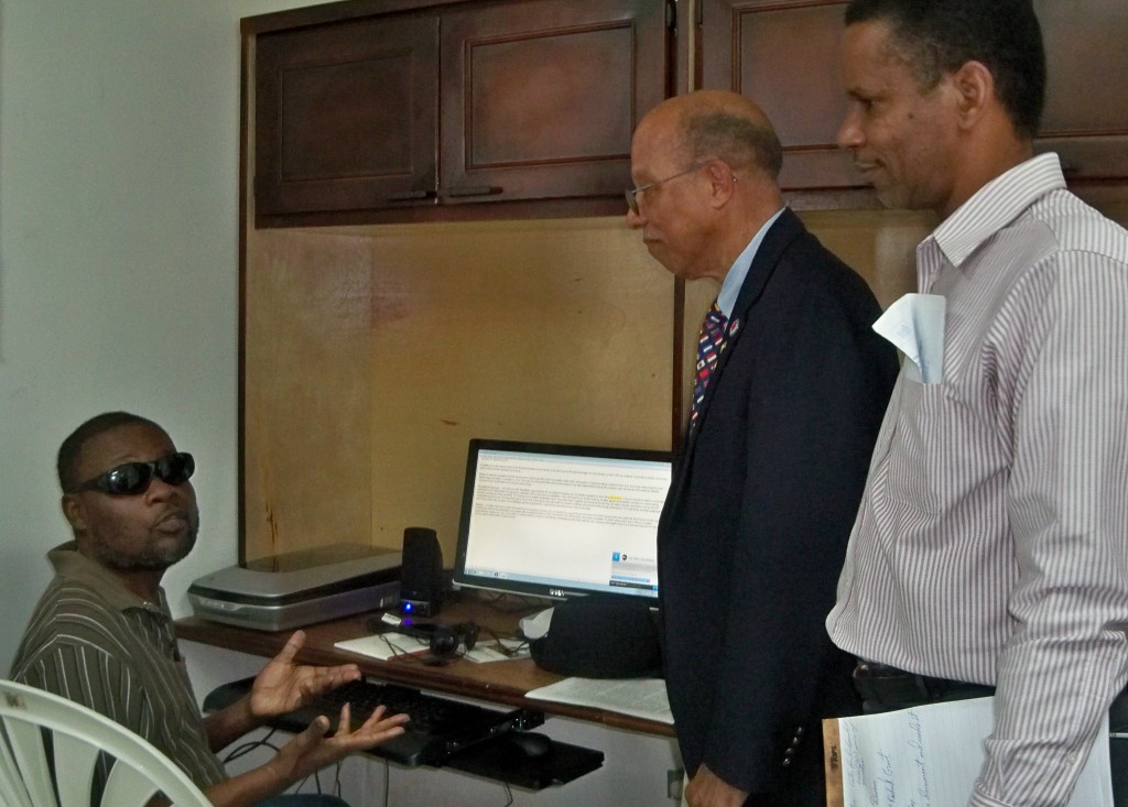 Client Henry Smith (left), works away at the new computer as Rotarian Richard Grant and WAPA Personnel Manager Douglas Canton look on.